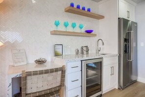 Una cocina moderna con horno empotrado, refrigerador de acero inoxidable y encimera de mármol.