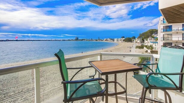 Un balcón con mesa y sillas que da a una playa y al océano.