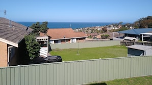 A residential area with houses, a green fence, and a view of the ocean. - Tura Views, 3 BR House (Tura Beach, Merimbula)