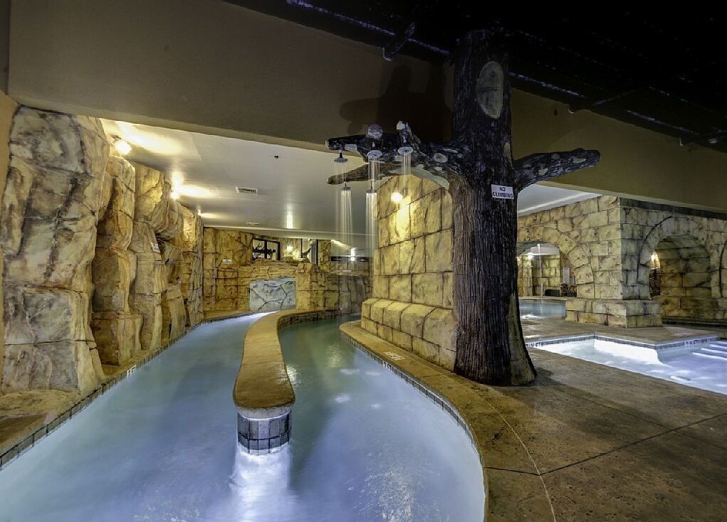 A spa area with a hot tub, stone walls, and a tree sculpture.