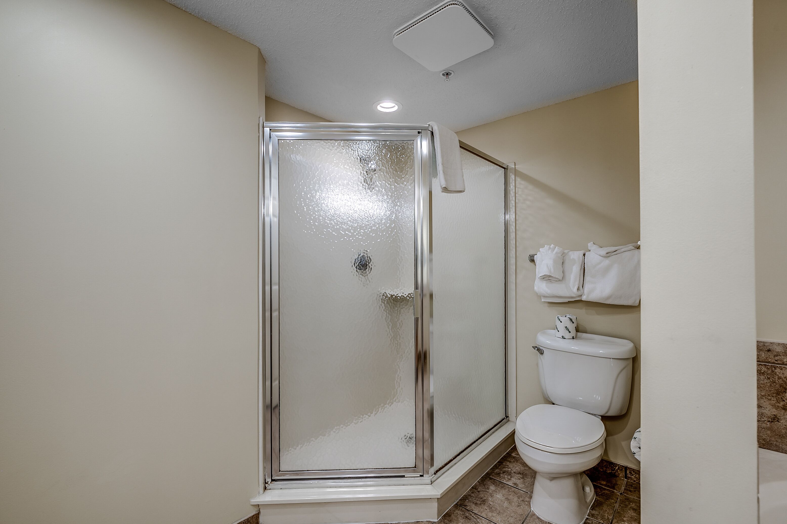 Un baño con ducha de vidrio, inodoro y perchero para toallas.