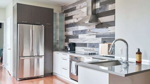 Una cocina moderna con un refrigerador de acero inoxidable, horno empotrado y una isla grande con fregadero.