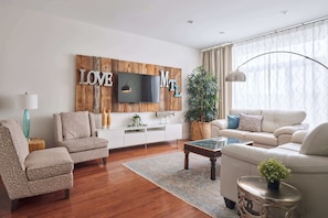 A modern living room with a wooden accent wall, a flat-screen TV, two sofas, a coffee table, and a side table with a plant. - MTLVR #13 | Central Urban Oasis, Sleeps 12, BBQ (Montreal)