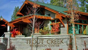 A lodge with a stone facade, wooden beams, and a green roof. - Lily Pad_Modern w/ AC! + Games, Smart TV's & HOA Amenities (Gym/HotTub/Sauna/Pool) (Truckee)