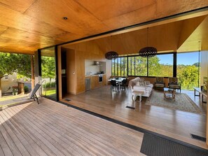 Une cuisine moderne avec un coin repas, de grandes fenêtres et une terrasse en bois.