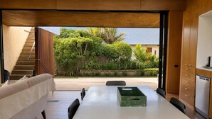 Uma cozinha moderna com área de refeições, uma escada que dá para área externa, e vista para o verde.