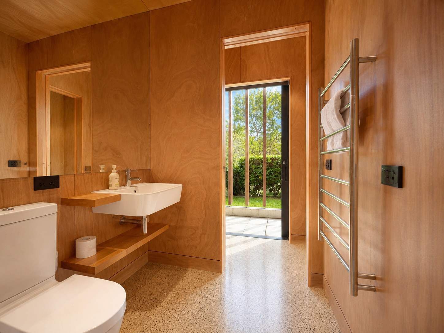 Un bagno moderno con finiture in legno, un lavandino bianco e un water.
