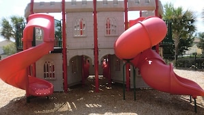 A playground with two red slides and a castle-like structure. - Newly Updated, 6BR Villa, South Facing Pool, Free water park (Kissimmee)