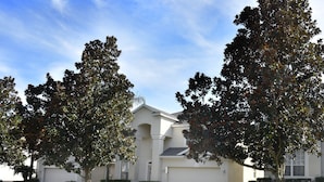 A residential house with a garage, surrounded by well-maintained lawns and trees. - Newly Updated, 6BR Villa, South Facing Pool, Free water park (Kissimmee)