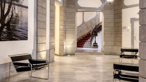 A spacious lobby with a high ceiling, a staircase, and two black metal chairs.