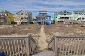 Un paseo marítimo frente a la playa que conduce a casas de playa coloridas con balcones.
