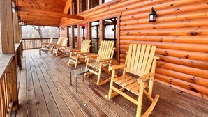 Eine Holzterrasse mit Adirondack-Stühlen und einer Laterne.