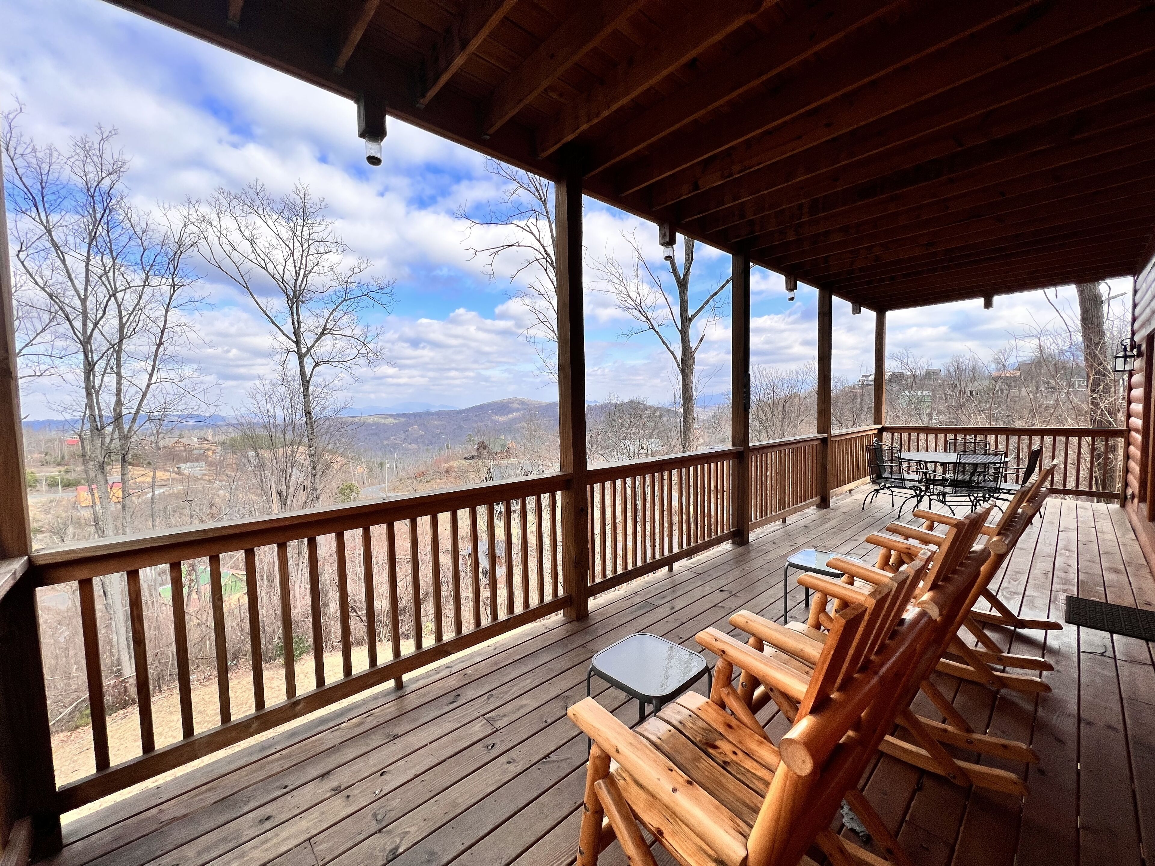 Una terraza de madera con una mesa y sillas, con vistas a un paisaje montañoso.