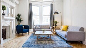 A living room with a fireplace, two sofas, a coffee table, and a large window with curtains. - MTLVR #08 | 10 min to downtown, terrace, A/C (Montreal)