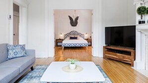 A modern bedroom with a large bed, bedside lamps, a TV, and a coffee table with a plant. - MTLVR #08 | 10 min to downtown, terrace, A/C (Montreal)
