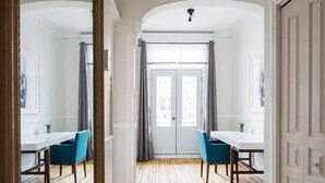 A room with a wooden floor, white walls, and a white door with grey curtains. There are two blue chairs and a white table. - MTLVR #08 | 10 min to downtown, terrace, A/C (Montreal)
