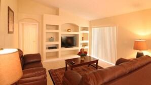 A living room with a TV, sofa, chairs, and a coffee table. - Beautiful 4 Bed/3 Bath Villa + Disney&Golf + Large South-Facing private Pool/Spa (Clermont)