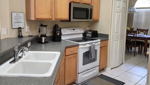 A kitchen with wooden cabinets, a microwave, a stove, and a sink. - Beautiful 4 Bed/3 Bath Villa + Disney&Golf + Large South-Facing private Pool/Spa (Clermont)