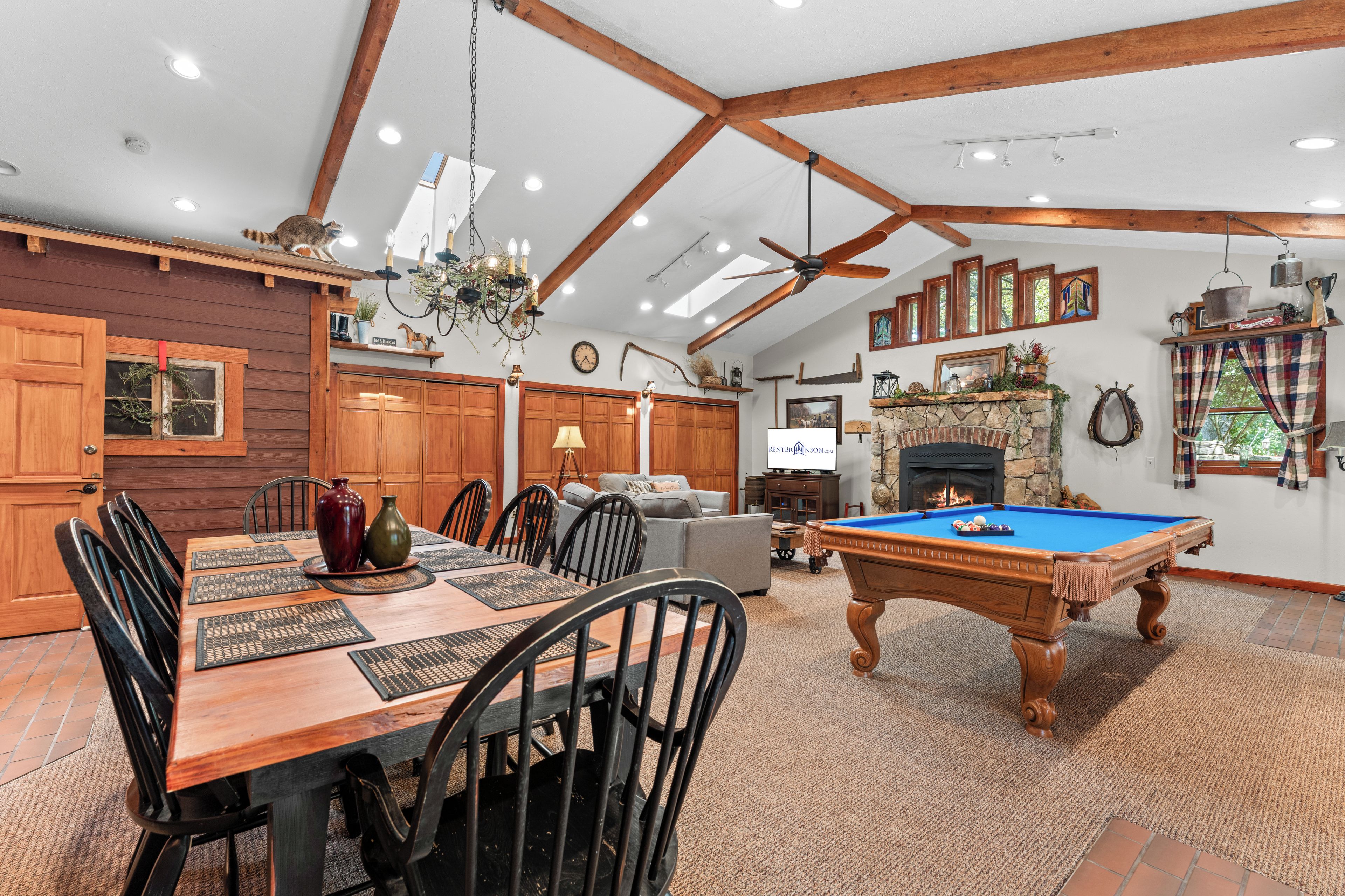 A spacious room with a pool table, wooden dining table, and a fireplace.