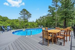 A wooden deck with a swimming pool, surrounded by trees and outdoor furniture. - Private One-Level Carriage House, Hot Tub, Pool Table, Dog Friendly & Car Charger (Blue Eye)