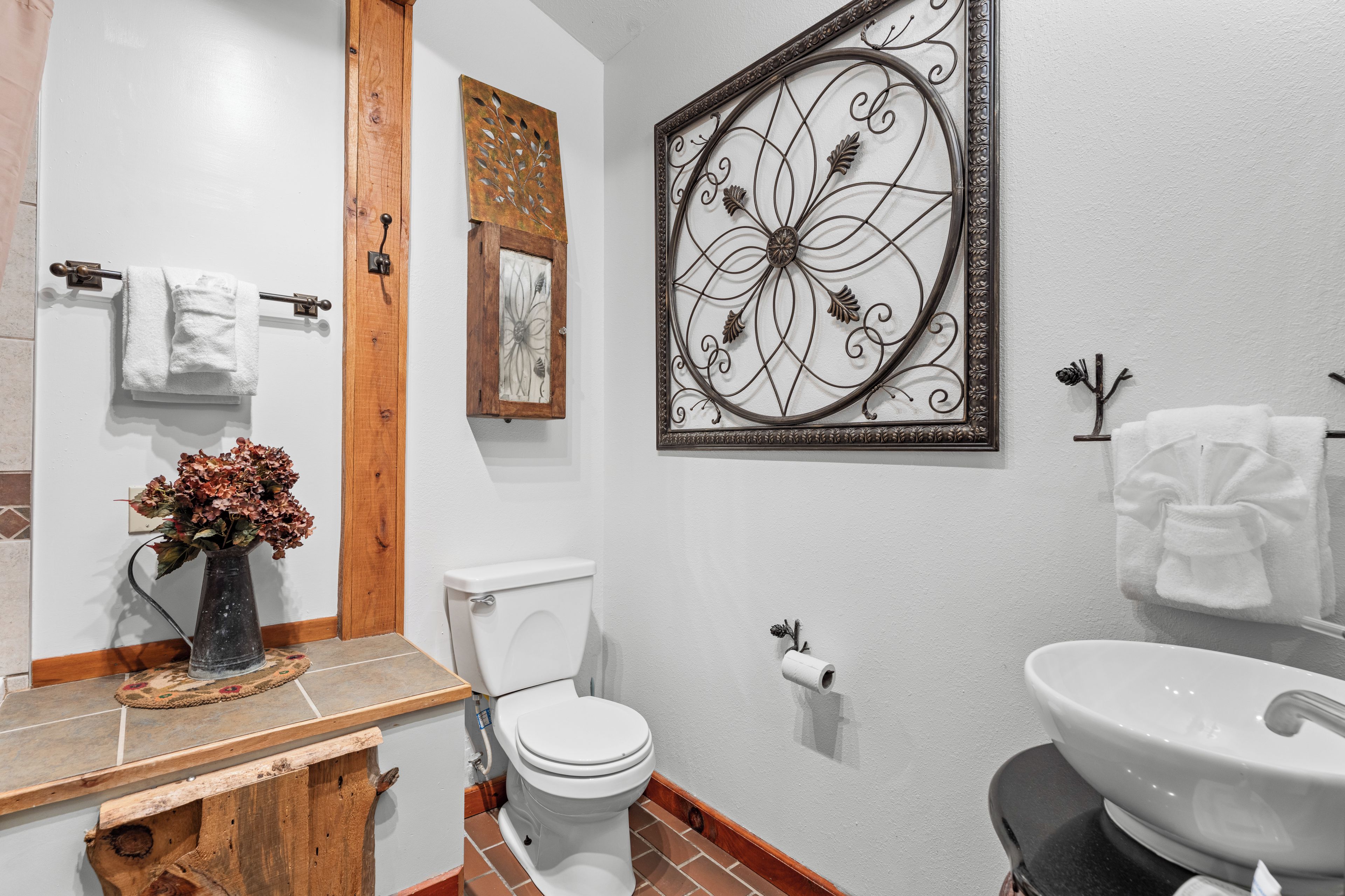 A bathroom with a toilet, sink, and decorative wall art.