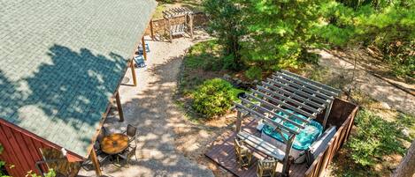 A patio area with a hot tub, wooden deck, and outdoor seating.