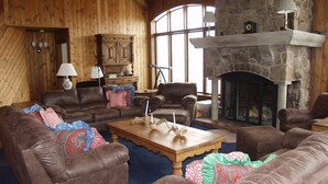 A cozy living room with leather sofas, a wooden coffee table, and a stone fireplace.