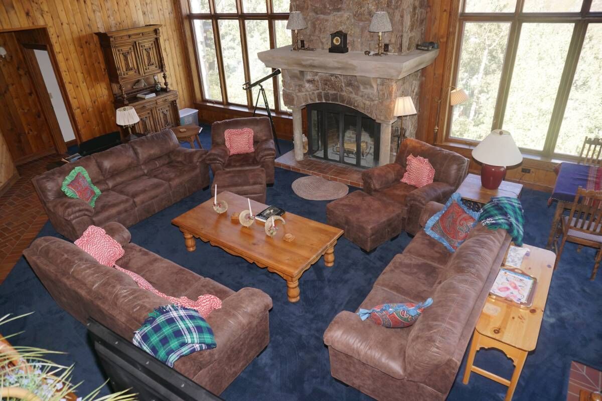 Una sala de estar acogedora con chimenea de piedra, sofás de cuero y una mesa de centro de madera.