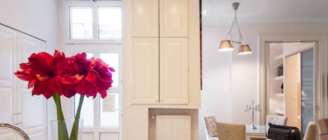 A kitchen with white cabinets, a granite countertop, and a vase with red flowers.
