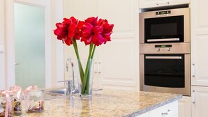 Een keuken met witte kasten, een granieten aanrechtblad en twee roestvrijstalen ovens.