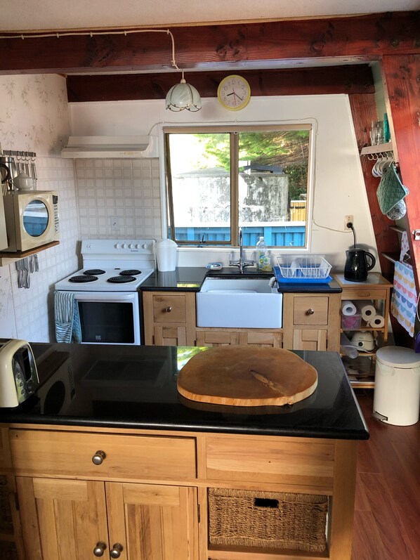 Una cocina con estufa, pileta y muebles bajos de madera.