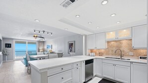 A modern kitchen with white cabinetry, a central island, and a view to the outside.