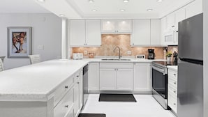 A modern kitchen with white cabinetry, a stainless steel refrigerator, a microwave, and a built-in oven.