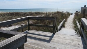 Una passerella di legno che conduce a una spiaggia, con un cartello che avverte della mancanza di bagnini.