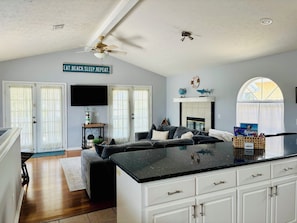 A spacious living area with a large sofa, a flat-screen TV, and a kitchen island. - Beautifully Decorated Home with Private Heated Pool Just Steps from the Ocean! (Panama City)