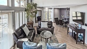 Un salón amplio con ventilador de techo, sofás de cuero, una mesa de centro y un televisor.
