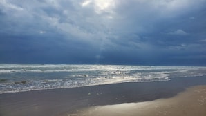 Una playa con olas y un cielo nublado.
