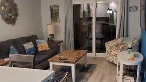 Un salon comprenant une table à manger, des chaises, un canapé et un ventilateur de plafond.