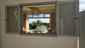 A room with a large window, a hanging light fixture, and a view of the outdoors.