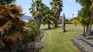 A well-maintained garden with palm trees, a stone pathway, and a grassy area.