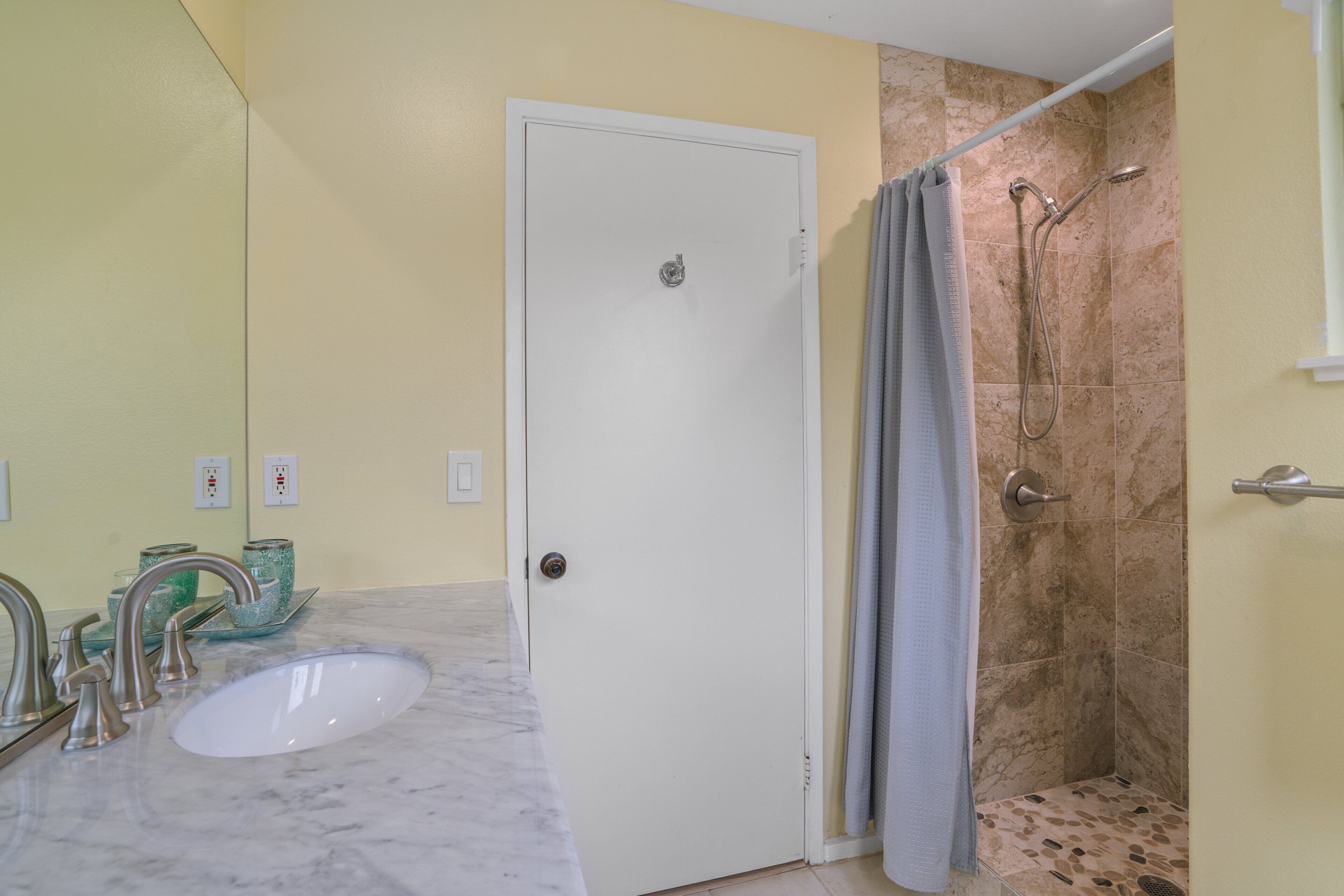 A bathroom with a white sink, a shower with a glass door, and a mirror above the sink.