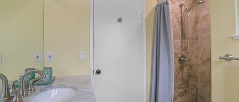 A bathroom with a white sink, a shower with a glass door, and a mirror above the sink.