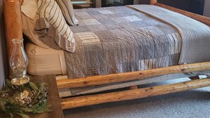 Un dormitorio con cama de madera, chimenea, ventana con persianas y un cuadro en la pared.