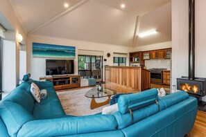 Ein modernes Wohnzimmer mit einem blauen Sofa, einem Glastisch und einem Kamin.