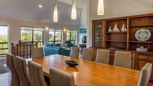 Uma ampla sala de jantar com mesa de madeira, cadeiras e luminárias pendentes.