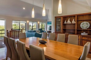 A spacious dining area with a wooden table, chairs, and pendant lights.
