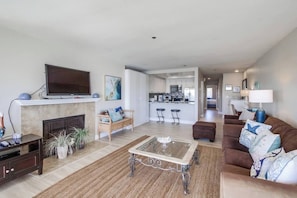 A spacious living room with a fireplace, a television, a coffee table, and a sofa.