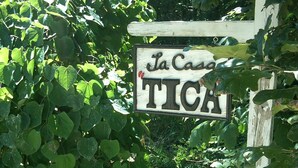 Ein hölzernes Schild mit der Aufschrift 'La Casa TICA', umgeben von dichtem Grün.