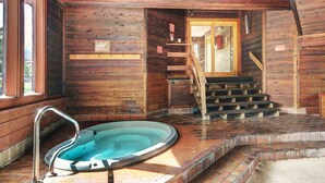 Een houten hut met een jacuzzi, een trap en een raam.