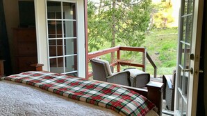Un dormitorio con una cama grande, un aparador de madera y un balcón con sillas de mimbre y una mesa.